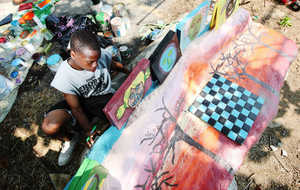 Deontae Brank, 16, worked on a free-form public art bench near Third Street Stuff. It's made of straw bales and chicken wire covered with layers of concrete, with a checkerboard embedded in the seat. It is part of a project by Youth GreenCorps, a grass-roots initiative that has engaged more than 40 teenagers in environmental, horticultural and artistic hands-on projects in northeast Lexington over the past several months. Photo by Pablo Alcala | Staff